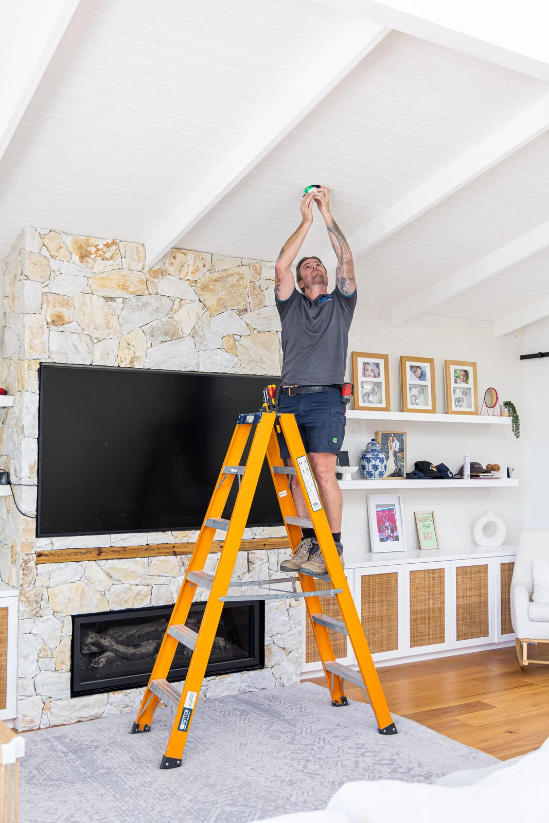 Electrician on a ladder installing a ceiling light