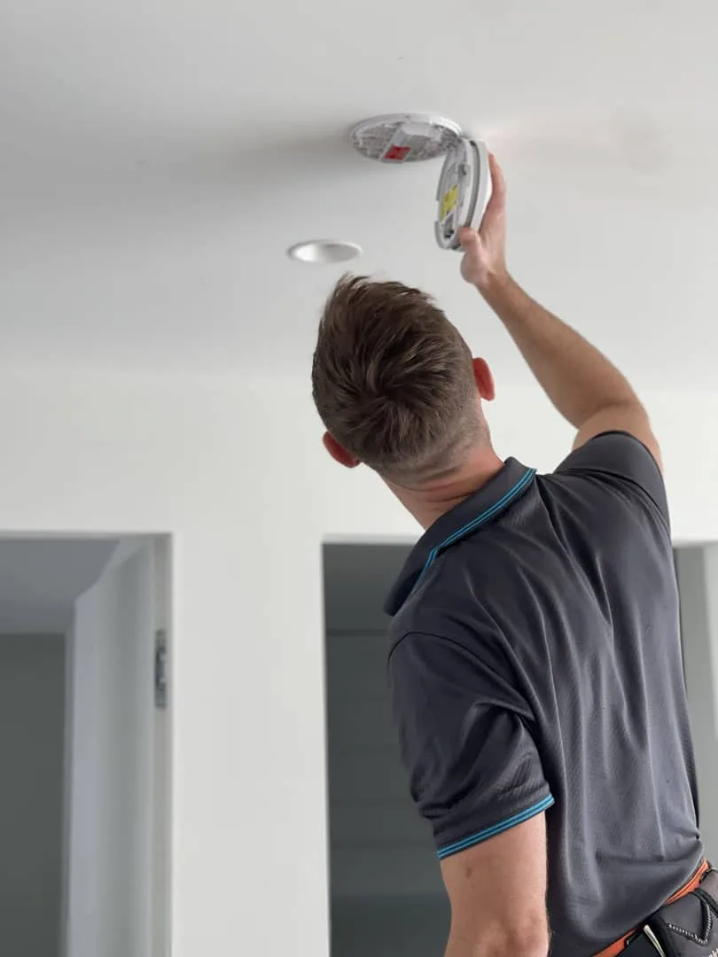 Electrician installing a ceiling downlight
