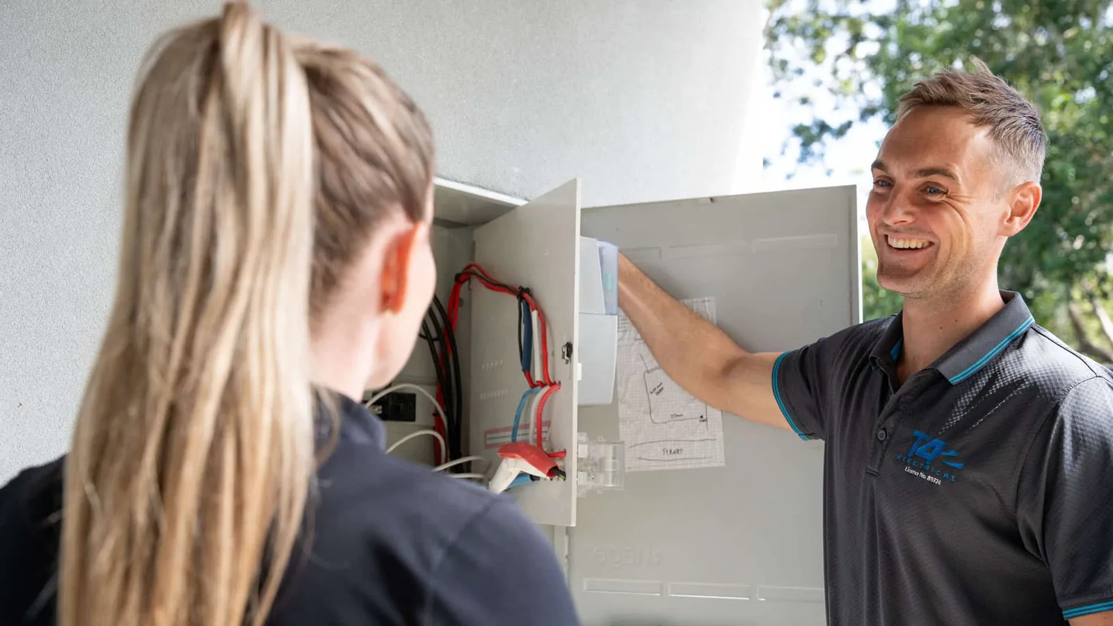 Electrician walking a customer through their switchboard